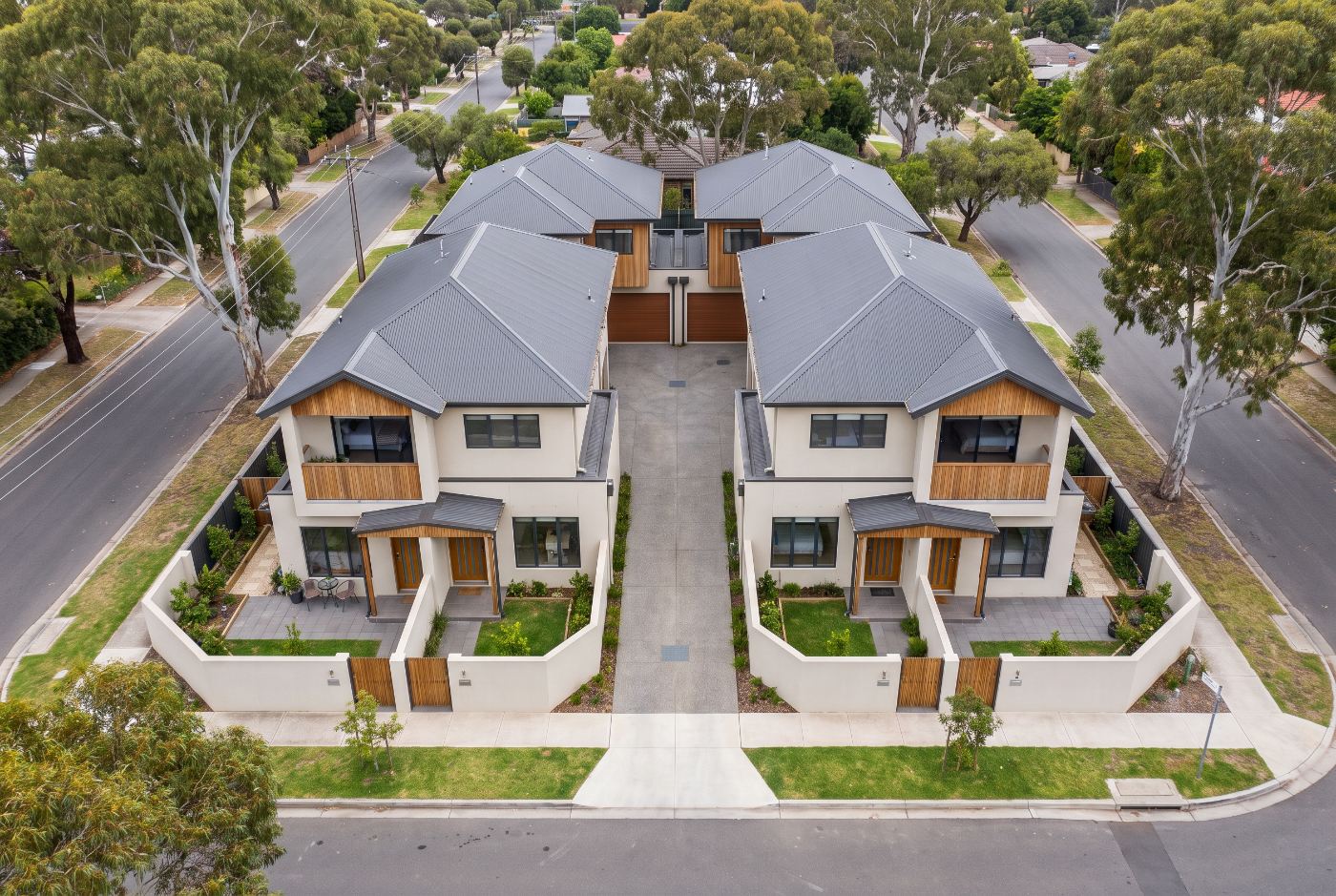Aerial view of four modern attached townhouses on a single suburban lot with a shared central driveway, a typical multi dwelling housing strata subdivision in NSW